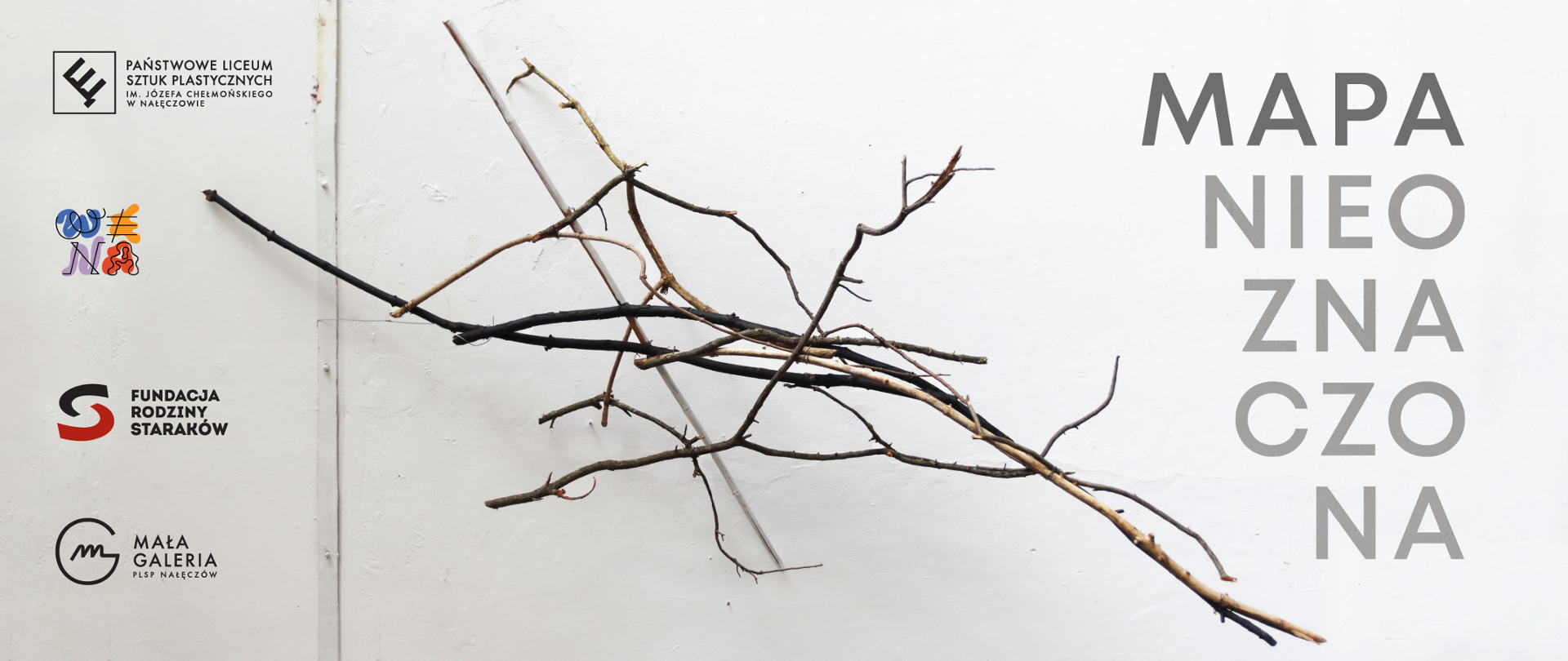 Baner do wystawy obiektów pt. Mapa Nieoznaczona, konstrukcja z patyków wisząca na ścianie.