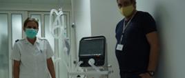 dwoje pracowników medycznych stoi obok respiratora oznakowanego naklejką Polish Aid