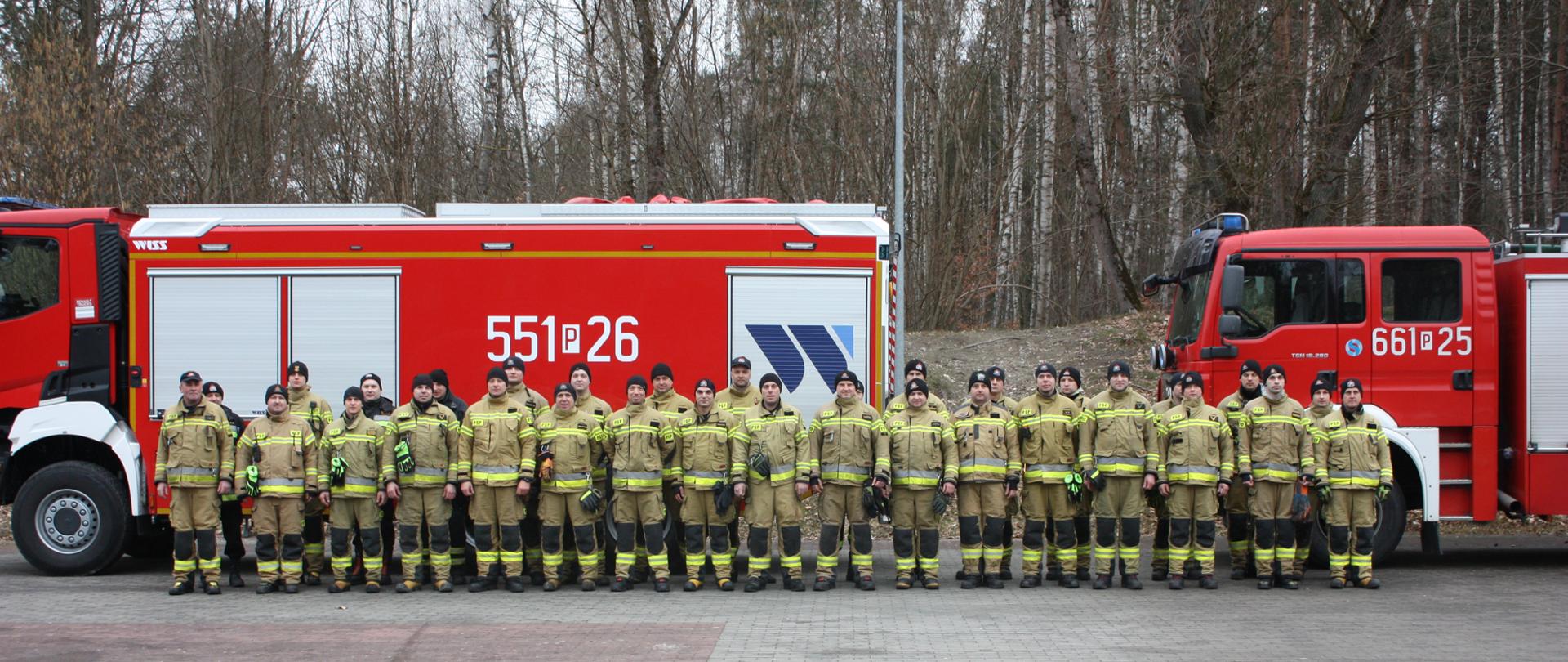 Na zdjęciu strażacy przed samochodami strażackimi 