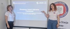 Dwie pracownice PSSE na tle slajdu "Światowy Dzień Zdrowia" i baneru z logo Państwowej Inspekcji Sanitarnej. 