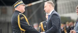 na zdjęciu strażak nadbrygadier Grzegorz Janowski oraz prezydent RP Andrzej Duda, stoją na przeciwko siebie i ściskają prawe dłonie