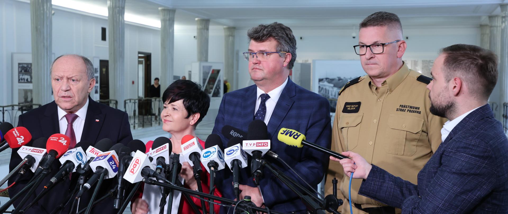 Zdjęcie przedstawia pięć osób podczas briefingu prasowego w gmachu Sejmu RP
