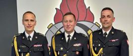 Na zdjęciu widoczny małopolski komendant wojewódzki Państwowej Straży Pożarnej st. bryg. Przemysław Przęczek, komendant powiatowy Państwowej Straży Pożarnej w Gorlicach mł. bryg. Waldemar Krok oraz przyjmujący akt powołania na stanowisko zastępcy komendanta powiatowego PSP w Gorlicach bryg. Dariusz Surmacz.
