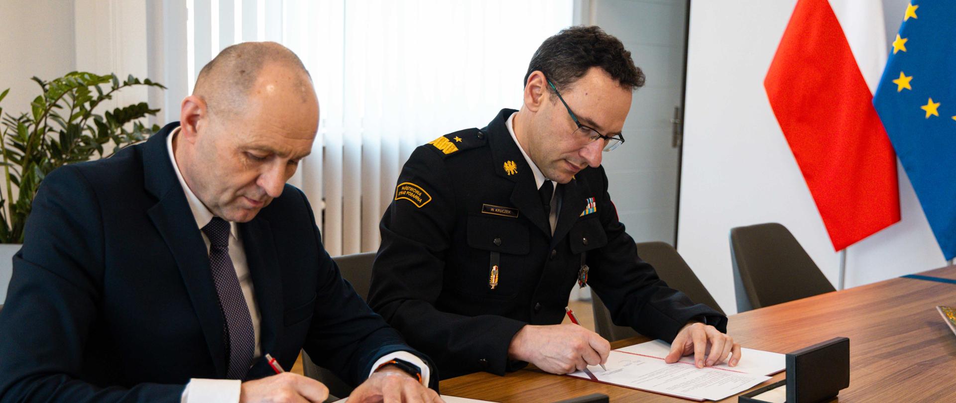 Dwie osoby podpisujące dokumenty.