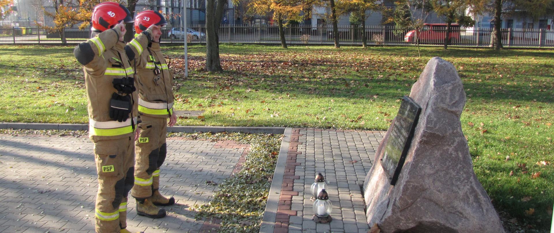 Strażacy salutują pod pomnikiem po zapaleniu zniczy.
