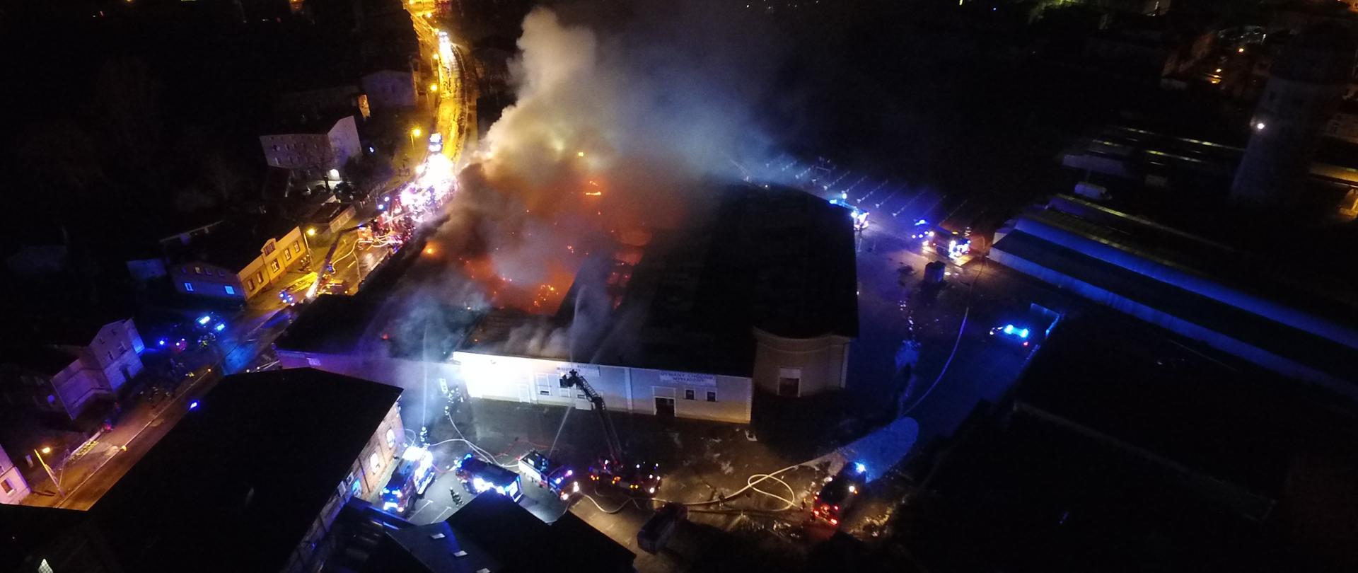 Zdjęcie wykonane z drona nocą podczas pożaru centrum handlowego. Prowadzona jest akcja gaśnicza.