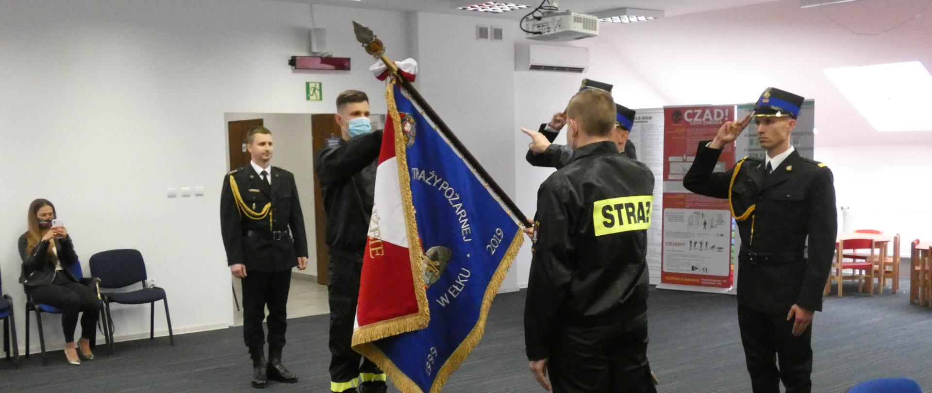 Na zdjęciu dwóch strażaków składa ślubowanie na sztandar Komendy, w tle poczet sztandarowy