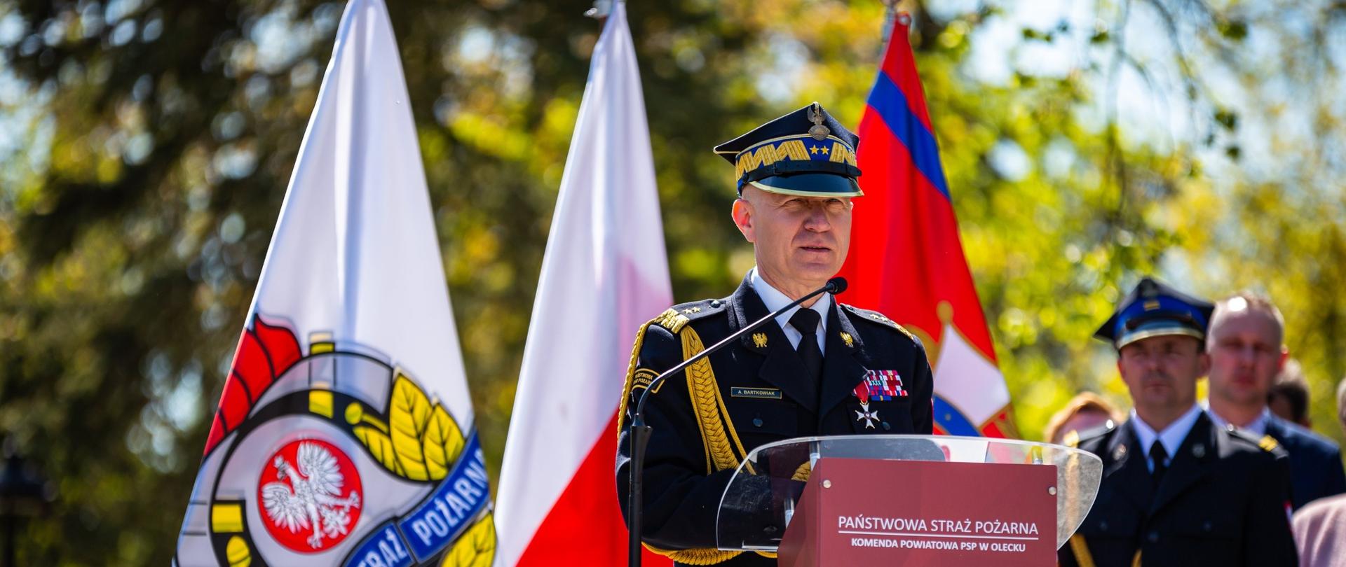 Na zdjęciu przy mównicy Komendant Główny PSP. W tle flagi Polski i PSP.