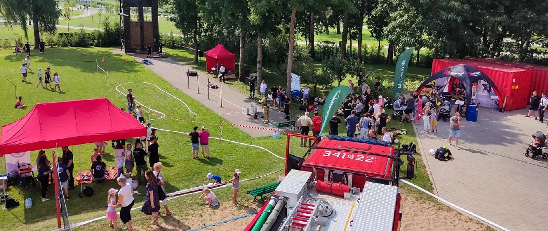 Zdjęcie przedstawia osoby cywilne, strażaków i sprzęt pożarniczy podczas rozgrywania konkurencji