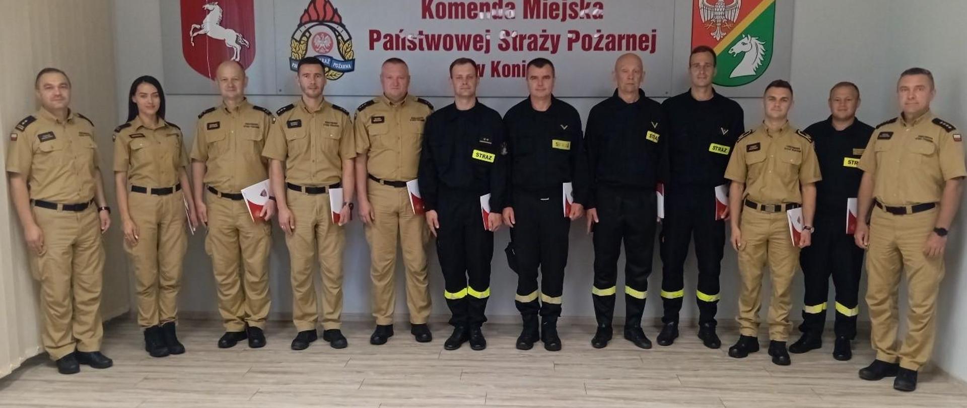 Na zdjęciu znajdują się komendanci oraz funkcjonariusze Komendy Miejskiej PSP w Koninie, którzy otrzymali mianowania na wyższe stanowiska służbowe.