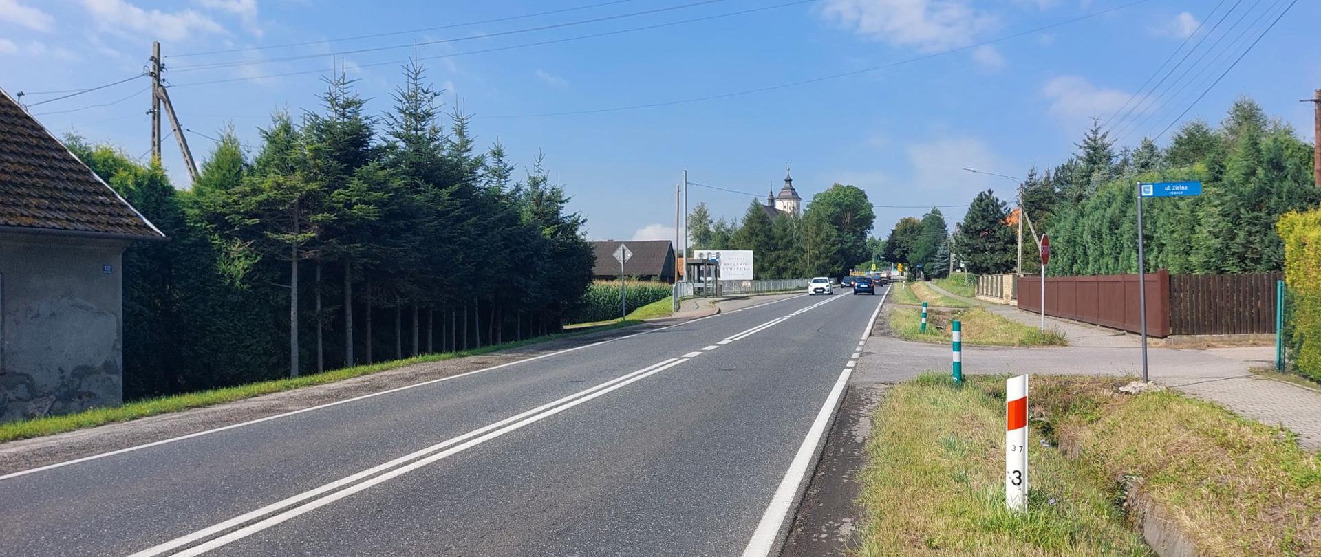 Droga krajowa nr 52 w Inwałdzie, po obu stronach trasy zabudowania, w tle kościół