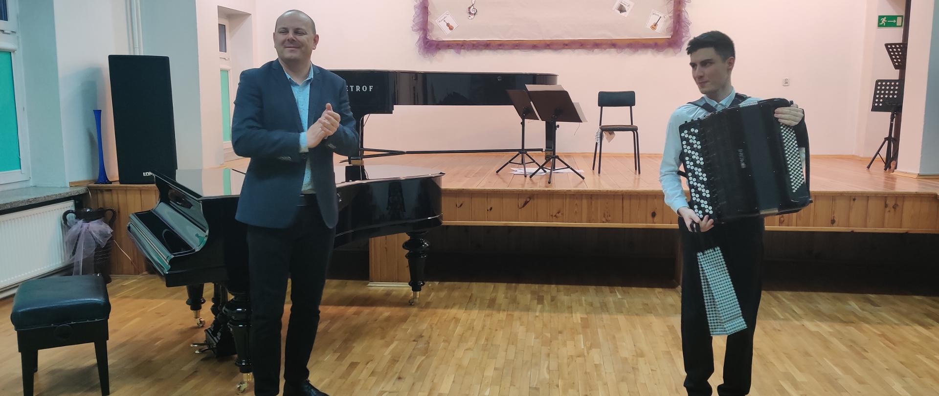 Zdjęcie przedstawiające Dominika Bezkorowajnego na akordeonie oraz dyrektora szkoły Bogusława Kłaka po koncercie w auli szkoły.