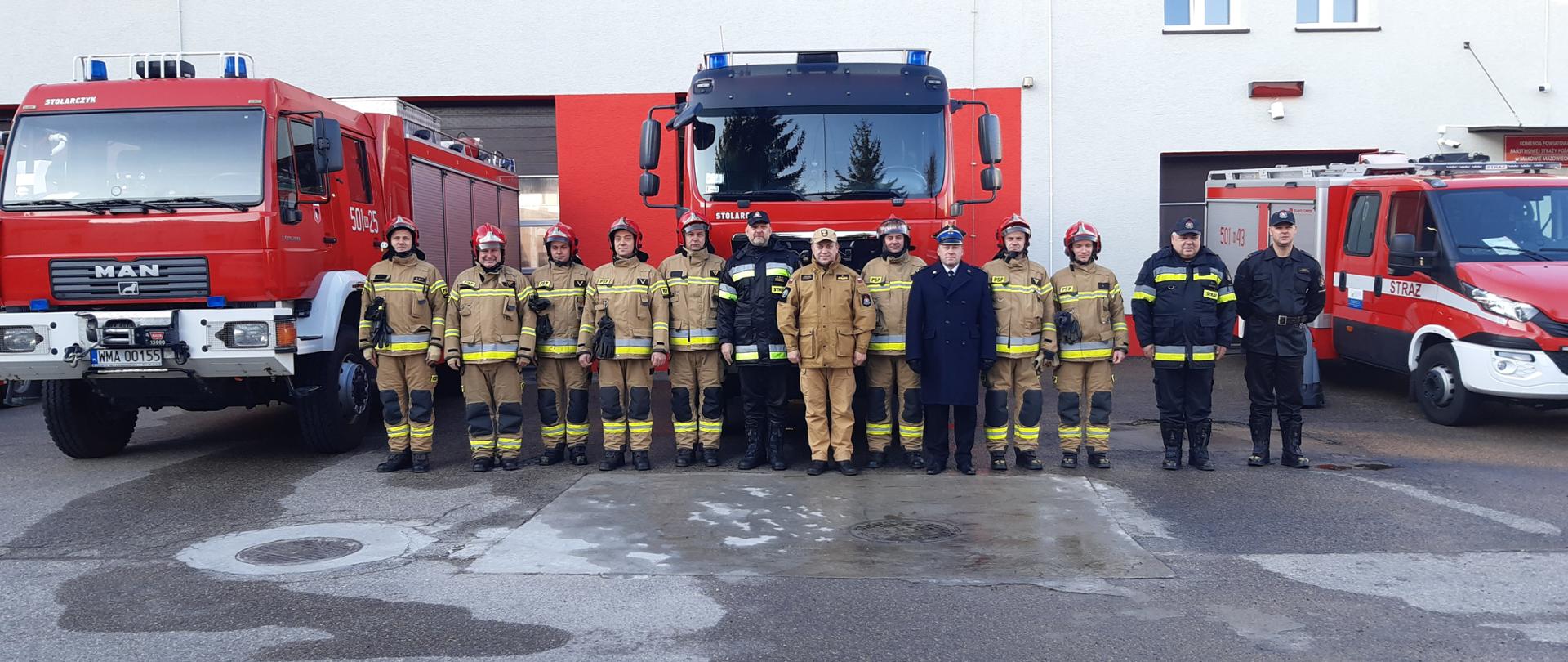 Funkcjonariusze KP PSP w Makowie Mazowieckim wraz z MKW PSP stoją w szeregu przed samochodami strażackimi