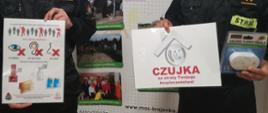 Na zdjęciu funkcjonariusze prezentują tablice informacyjne na temat tlenku węgla na tle baneru MOS-u