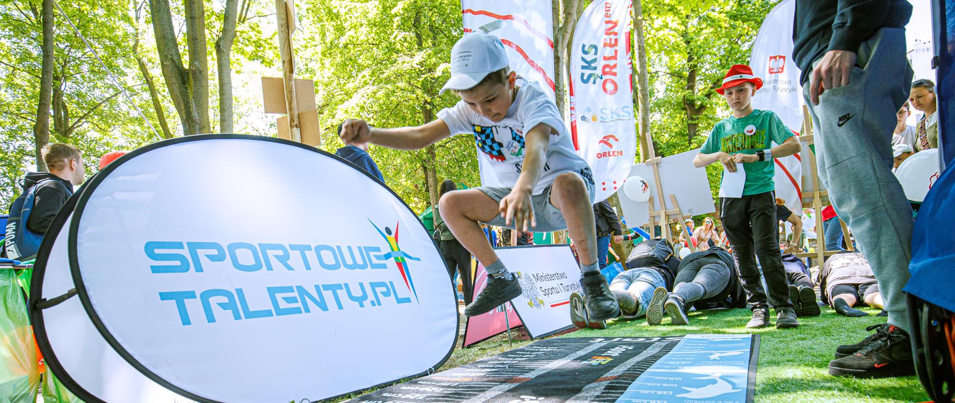 Na zdjęciu widać chłopca, który na stoisku Instytutu Sportu skacze w dal. Skok w dal jest jednym z testów w ministerialnym programie Sportowe Talenty