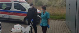 Strażak przekazuje środki ochrony indywidualnej personelowi medycznemu w punkcie sczepień 