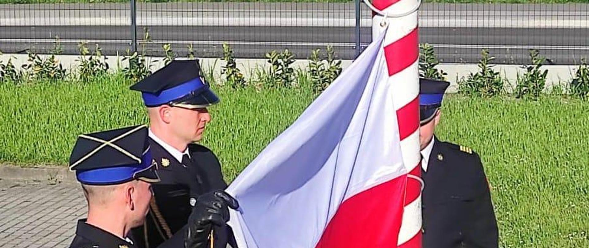 Zdjęcie przedstawia wciąganie flagi na maszt.