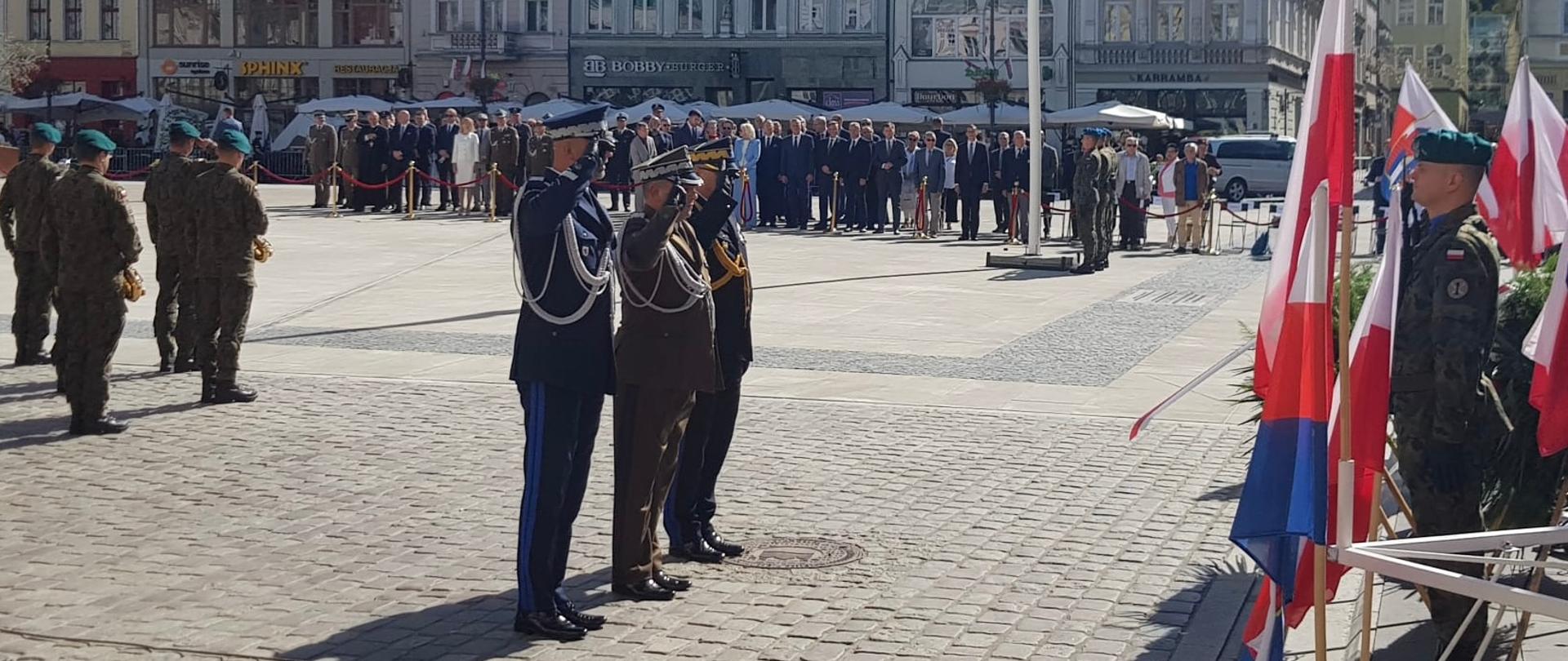 Złożenie kwiatów pod Pomnikiem. W delegacji służb mundurowych kujawsko-pomorski komendant wojewódzki PSP. W tle architektura Starego Rynku.