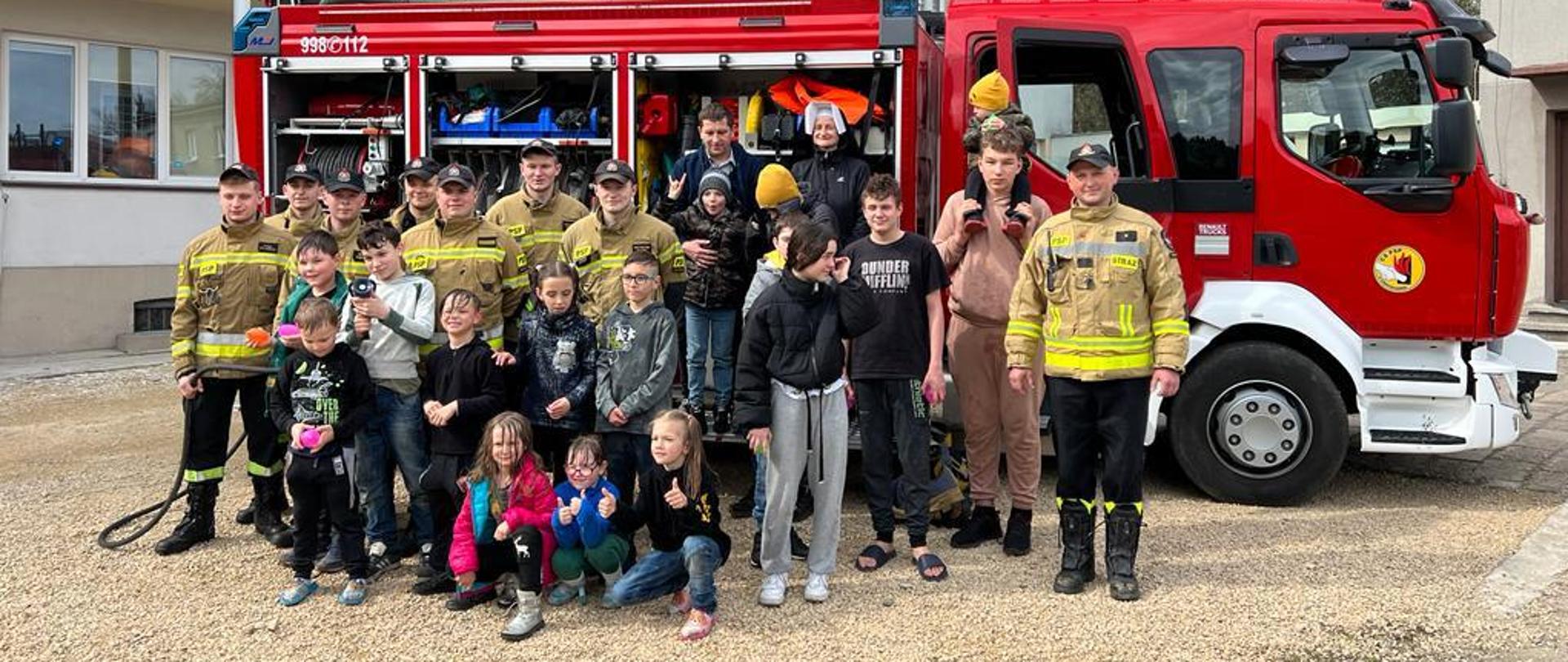Grupowe zdjęcie wychowanków zakładu opiekuńczo-leczniczego wraz ze strażakami na tle samochodu bojowego Centralnej Szkoły PSP