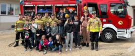 Grupowe zdjęcie wychowanków zakładu opiekuńczo-leczniczego wraz ze strażakami na tle samochodu bojowego Centralnej Szkoły PSP