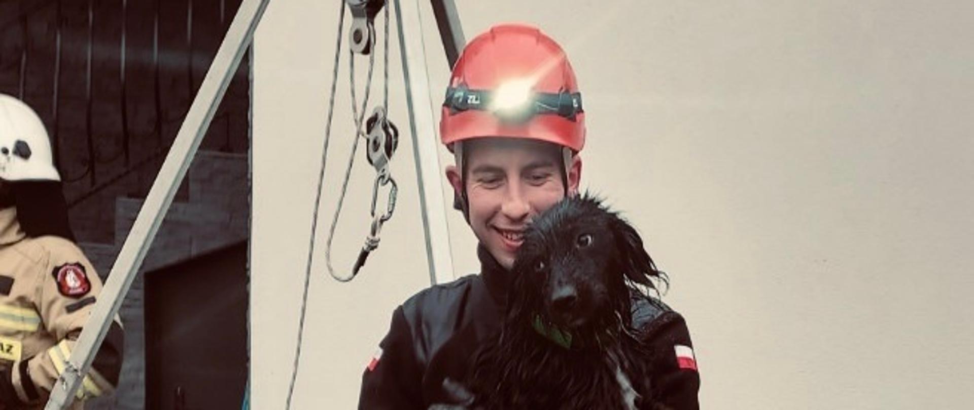 Zdjęcie przedstawia ratownika z psem na rękach.