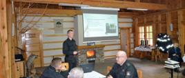 Strażak omawia zagadnienia wyświetlane na rzutniku multimedialnym podczas narady kadry kierowniczej Państwowej Straży Pożarnej województwa pomorskiego. 