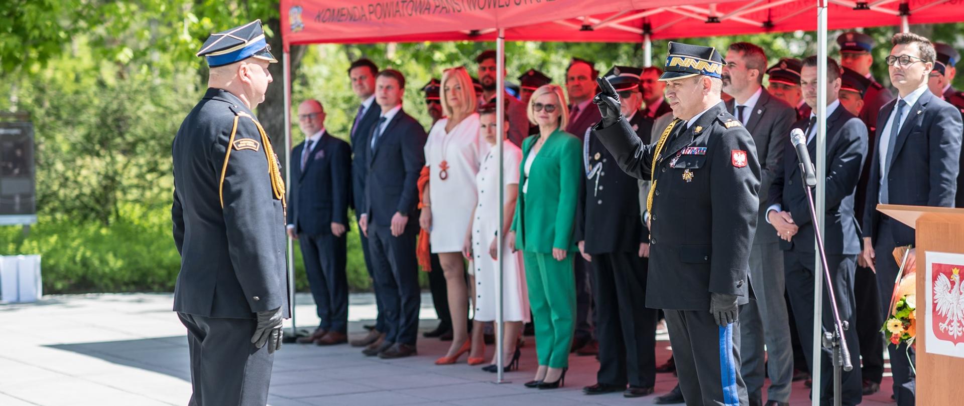 Na fotografii, dowódca uroczystości, mł. bryg. Radosław Podgórski, składający meldunek Mazowieckiemu Komendantowi Wojewódzkiemu, nadbryg. Jarosławowi Nowosielskiemu z okazji obchodów dnia strażaka.