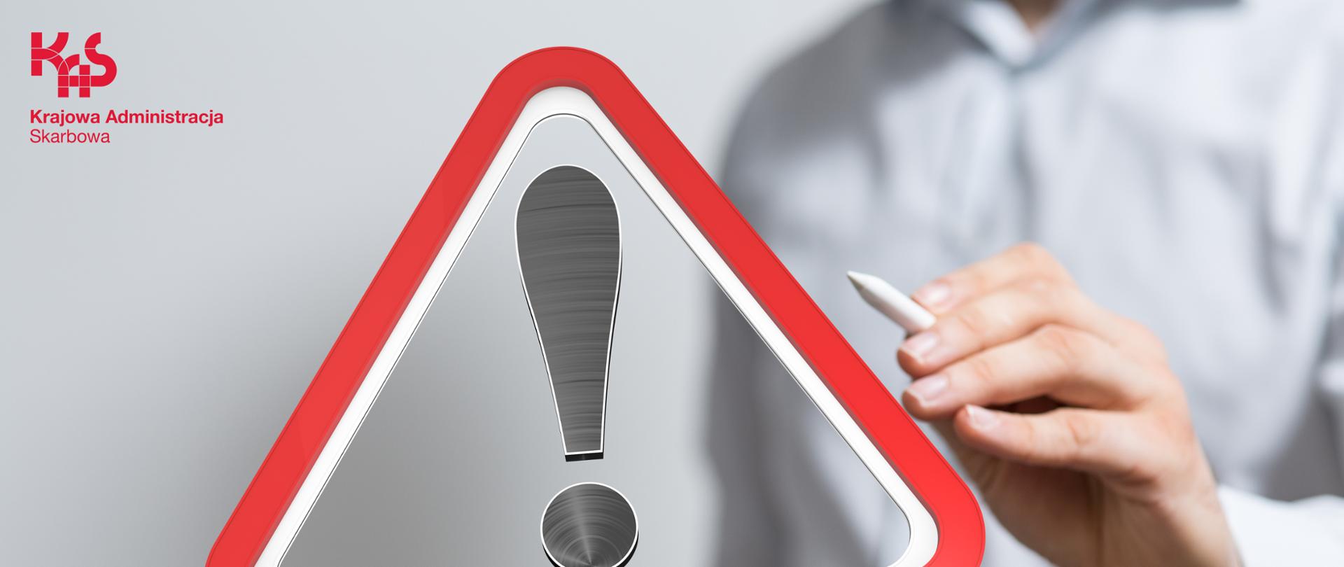 Znak ostrzeżenia, z tyłu widoczna ręka z długopisem 