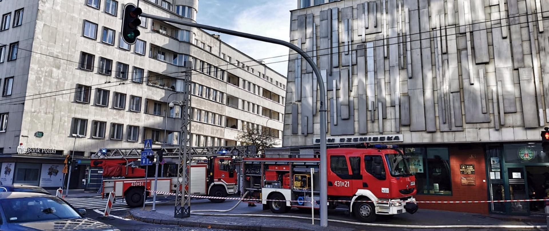Na ulicy przed budynkiem stoi samochód gaśniczy