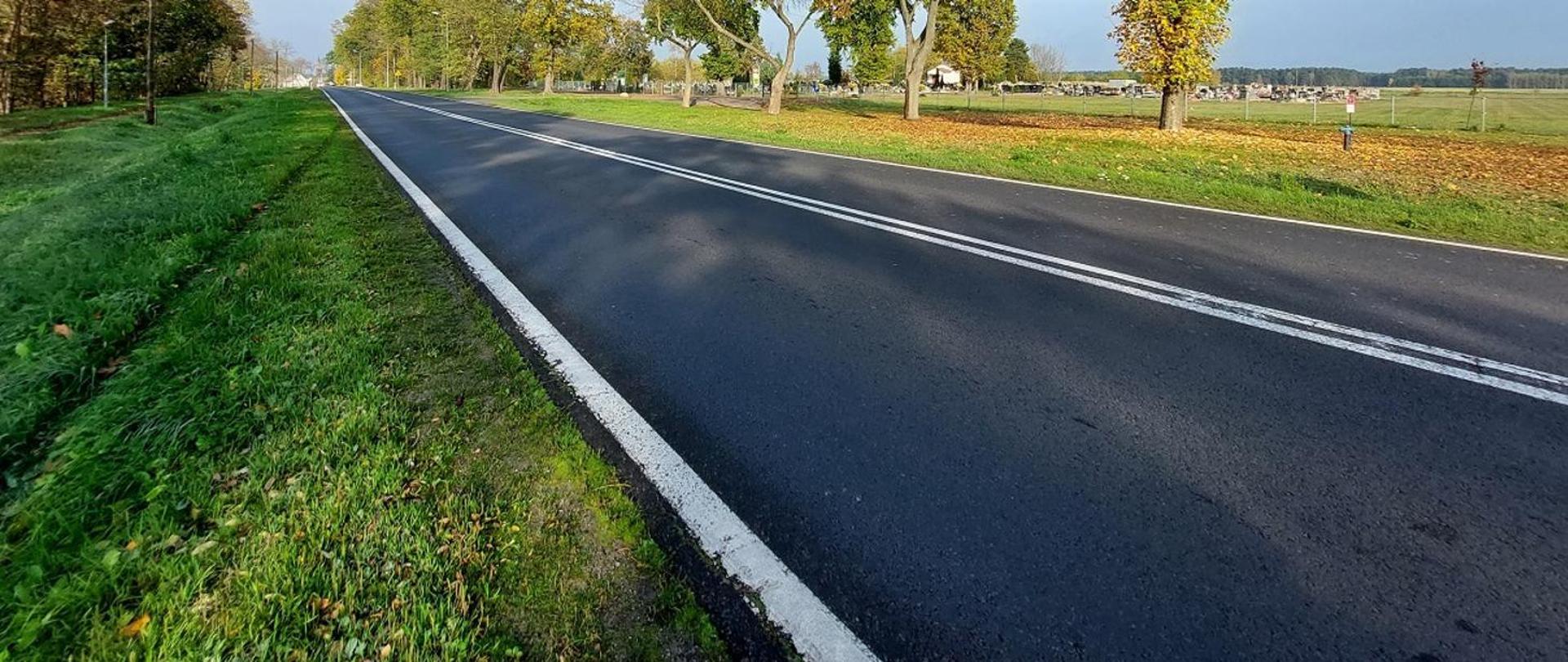 Na zdjęciu Droga krajowa jednojezdniowa. Brak pojazdów poruszających się po drodze. Zielone pobocza.