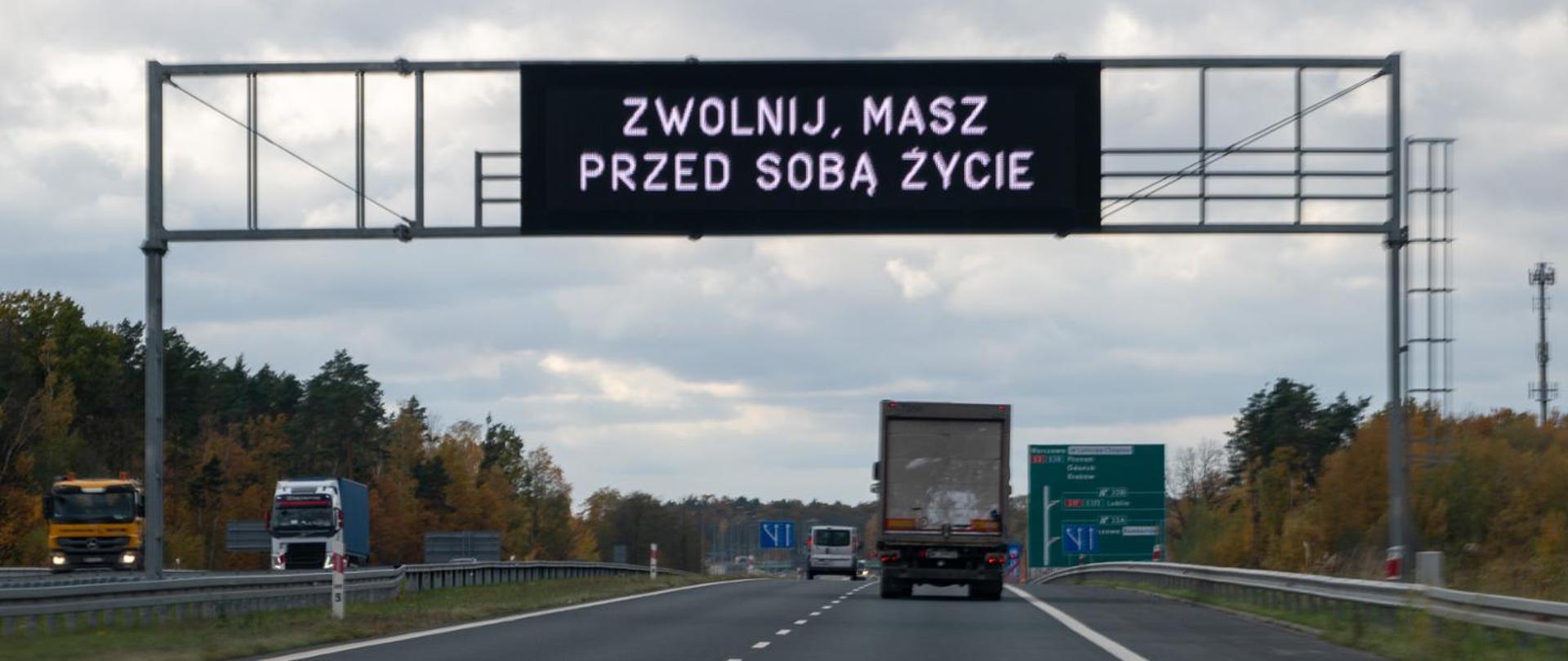 Tablica z wyświetlaną informacją zamontowana na bramownicy nad drogą ekspresową, na tablicy napis "Zwolnij, masz przed sobą życie" 