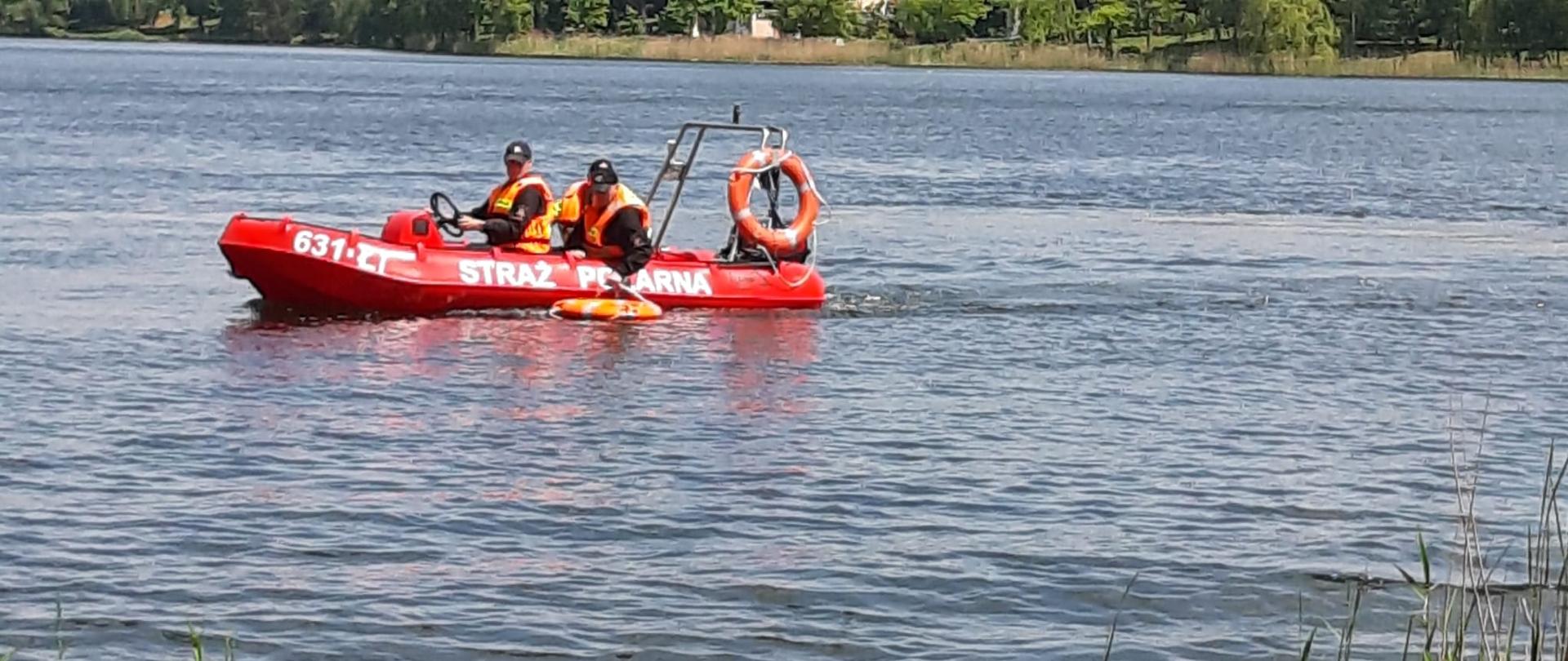 Na zdjęciu widać strażaków pływających w łodzi na jeziorze 