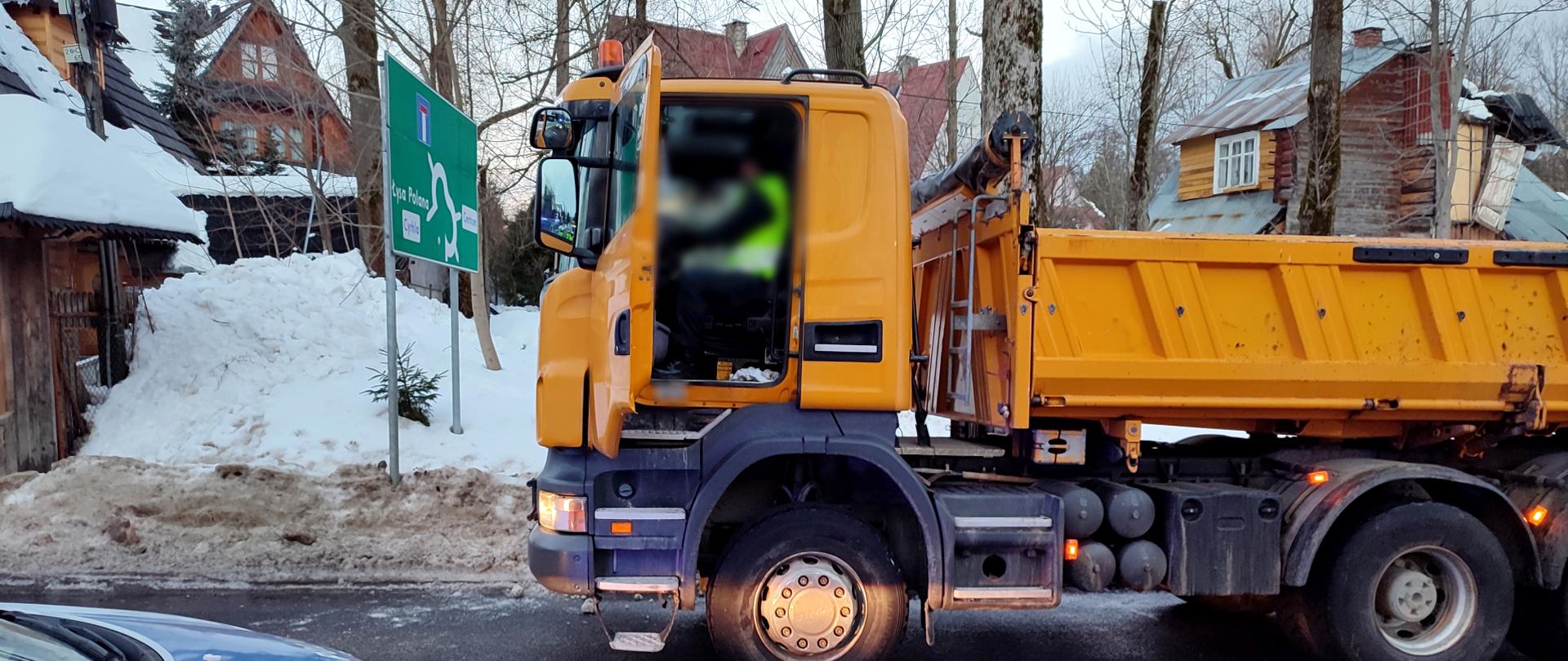 Inspektorzy małopolskiej Inspekcji Transportu Drogowego pobrali dane z tachografu oraz karty kierowcy ciężarówki. Na zdjęciu miejsce tragedii. Na pierwszym planie pojazd ciężarowy koloru pomarańczowego. Po lewej policyjny radiowóz.
