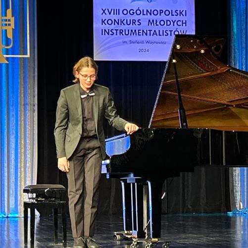 Zdjęcie przedstawia scenę jasielskiego domu kultury a na niej kłaniającego się do publiczności Gabriela Kuizinasa. Obok chłopca czarny fortepian. 