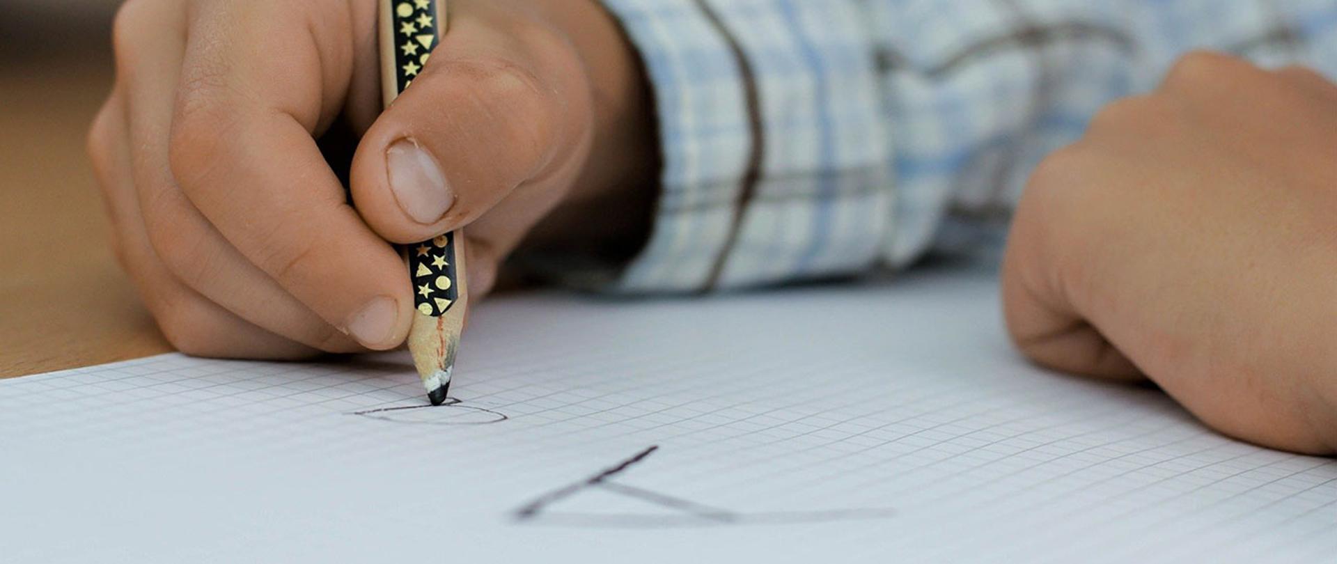 Na zdjęciu: dziecko piszące litery