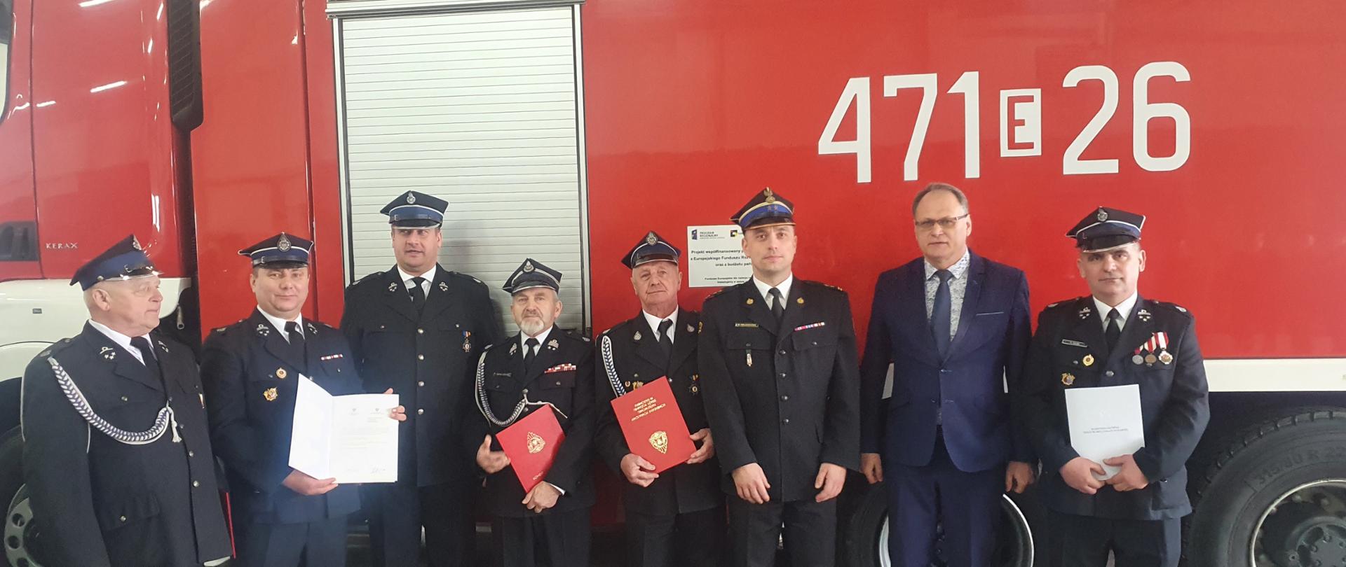 na głównym planie strażacy oraz przedstawiciele władz samorządowych z terenu powiatu radomszczańskiego na tle samochodu gaśniczego