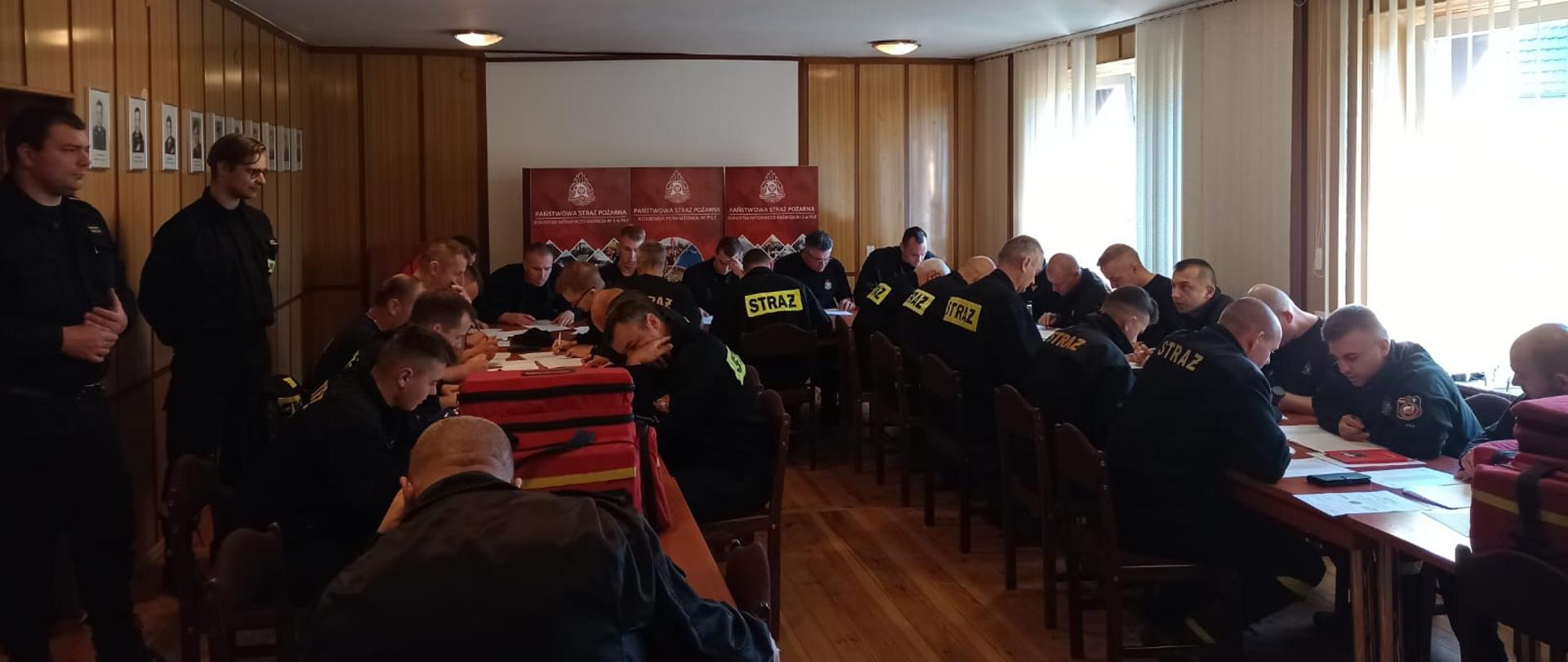 Na zdjęciu widać strażaków piszących test.