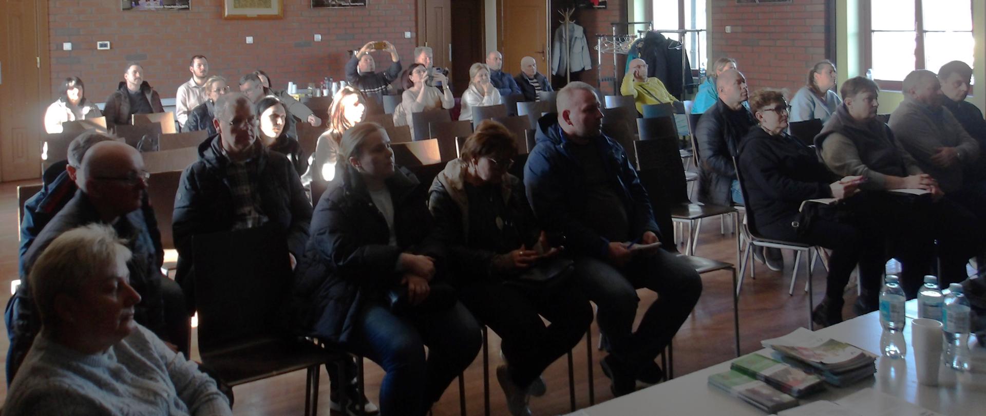 Na sali 30 rolników siedzi na krzesłach ustawionych w kilku rzędach.i słucha wystąpienia prelegenta.