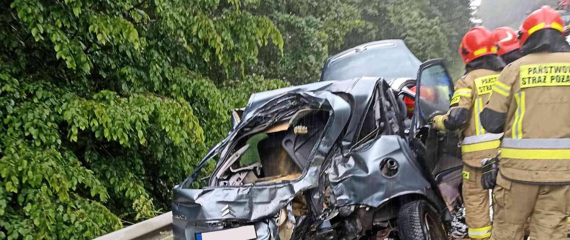 Rozbity samochód stojący na poboczu drogi.