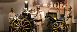 Sala sikawek, Arkadiusz ubrany w mundur historycznego strażaka na tle pierwszej sikawki parowej