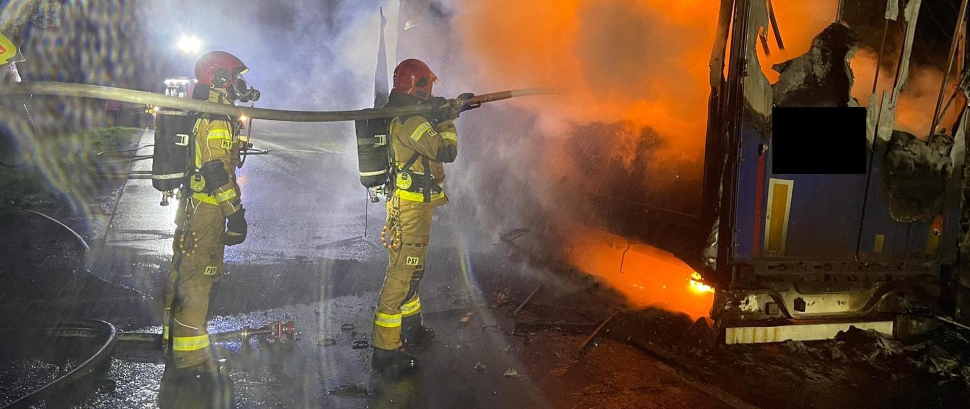 Na zdjęciu widnieją strażacy podczas prowadzenia działań ratowniczych związanych z pożarem przyczepy ciężarowej. 