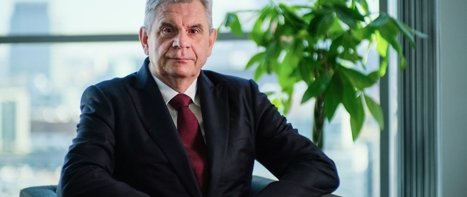 Jacek Oko, prezes UKE - zdjęcie portretowe, w tle zielona roślina