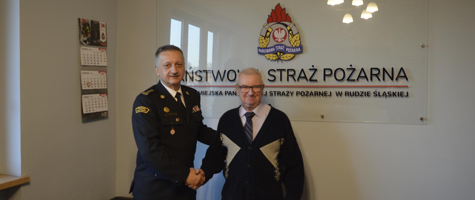 Zdjęcie przedstawia Komendanta Miejskiego PSP w Rudzie Śląskiej podczas wręczenia dokumentu o przyznaniu świadczenia ratowniczego dla druha OSP.