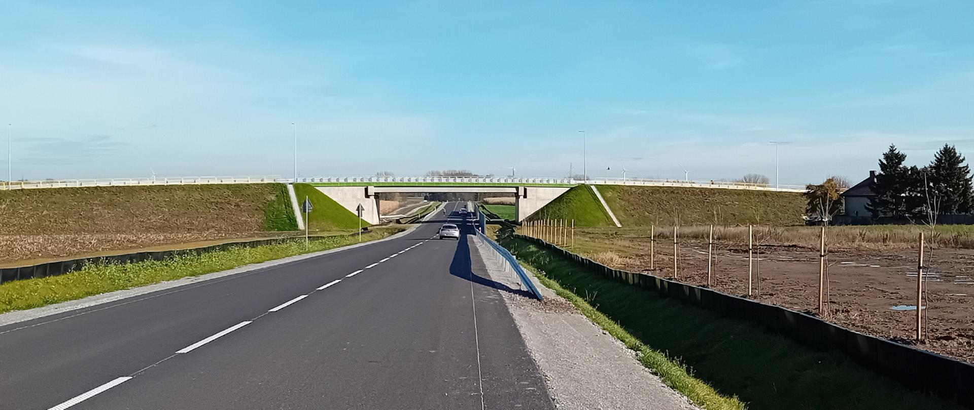 Obwodnica Koźmina Wielkopolskiego na drodze krajowej nr 15 z wiaduktem nad trasą i samochodami na jezdni.