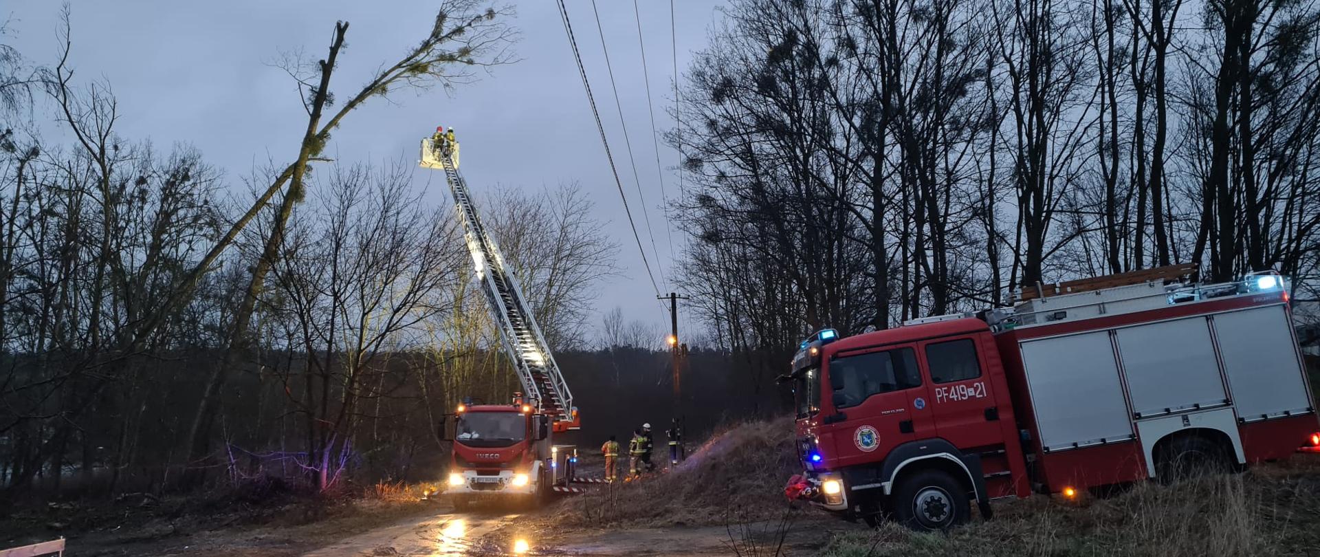 Strażacy na drabinie usuwają skutki wichury 