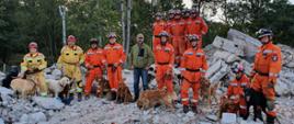 Psy ratownicze na tle skał z ratownikami pozują do zdjęcia.