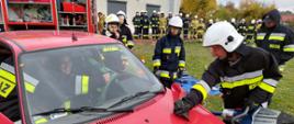 Zdjęcie przedstawia druhów OSP podczas szkolenia podstawowego. Strażacy przy pomocy urządzeń hydraulicznych wykonują dostęp do uwięzionej osoby w samochodzie osobowym. 