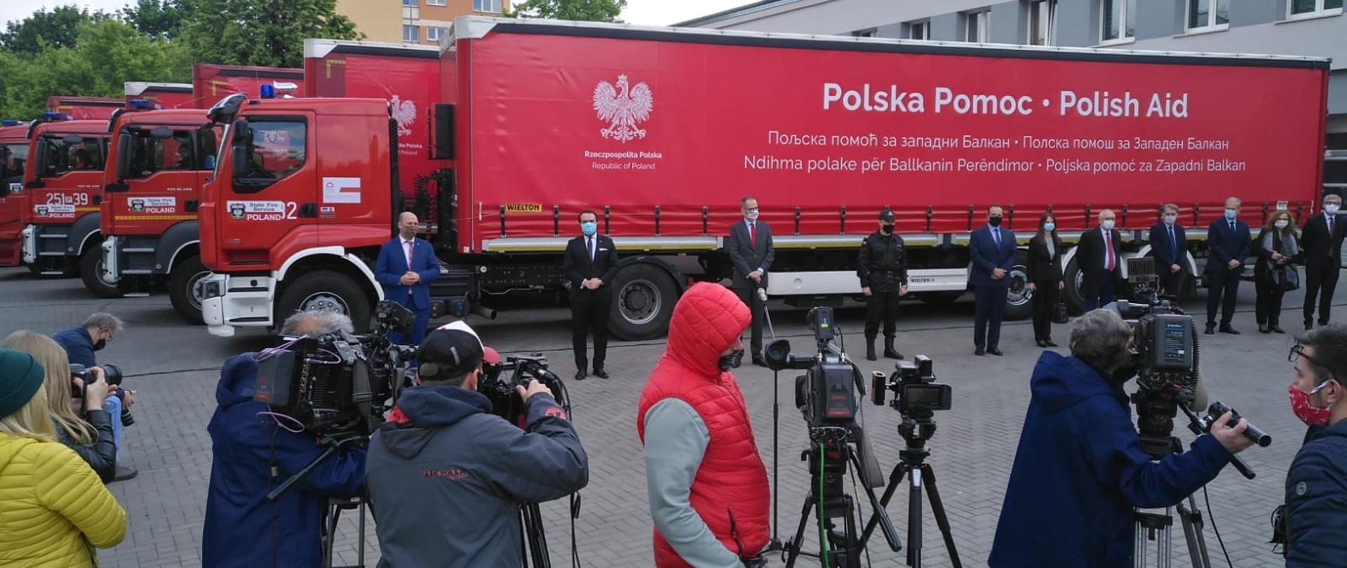 Polscy strażacy z pomocą dla Bałkanów – na zdjęciu na pierwszym planie dziennikarze, a w tle ciężarówki z pomocą humanitarną.