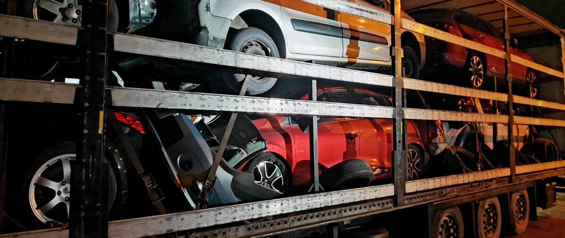 Bok naczepy z zużytymi częściami i rozbitymi samochodami.