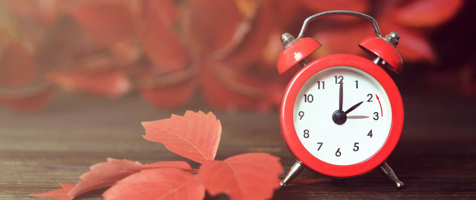 zegarek na stole, obok suchy liść symbolizujący jesień